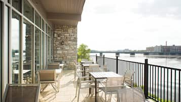 A terrace with outdoor seating and a view of a river.