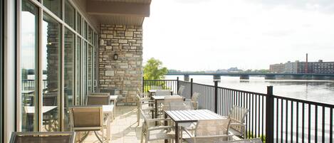 A terrace with outdoor seating and a view of a river.