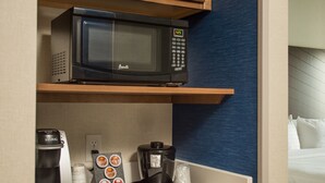 Een kleine keuken met een magnetron, koffiezetapparaat en een kleine koelkast.