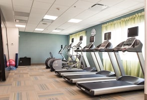 Un gimnasio con cintas de correr, elípticas y pelotas de ejercicio.