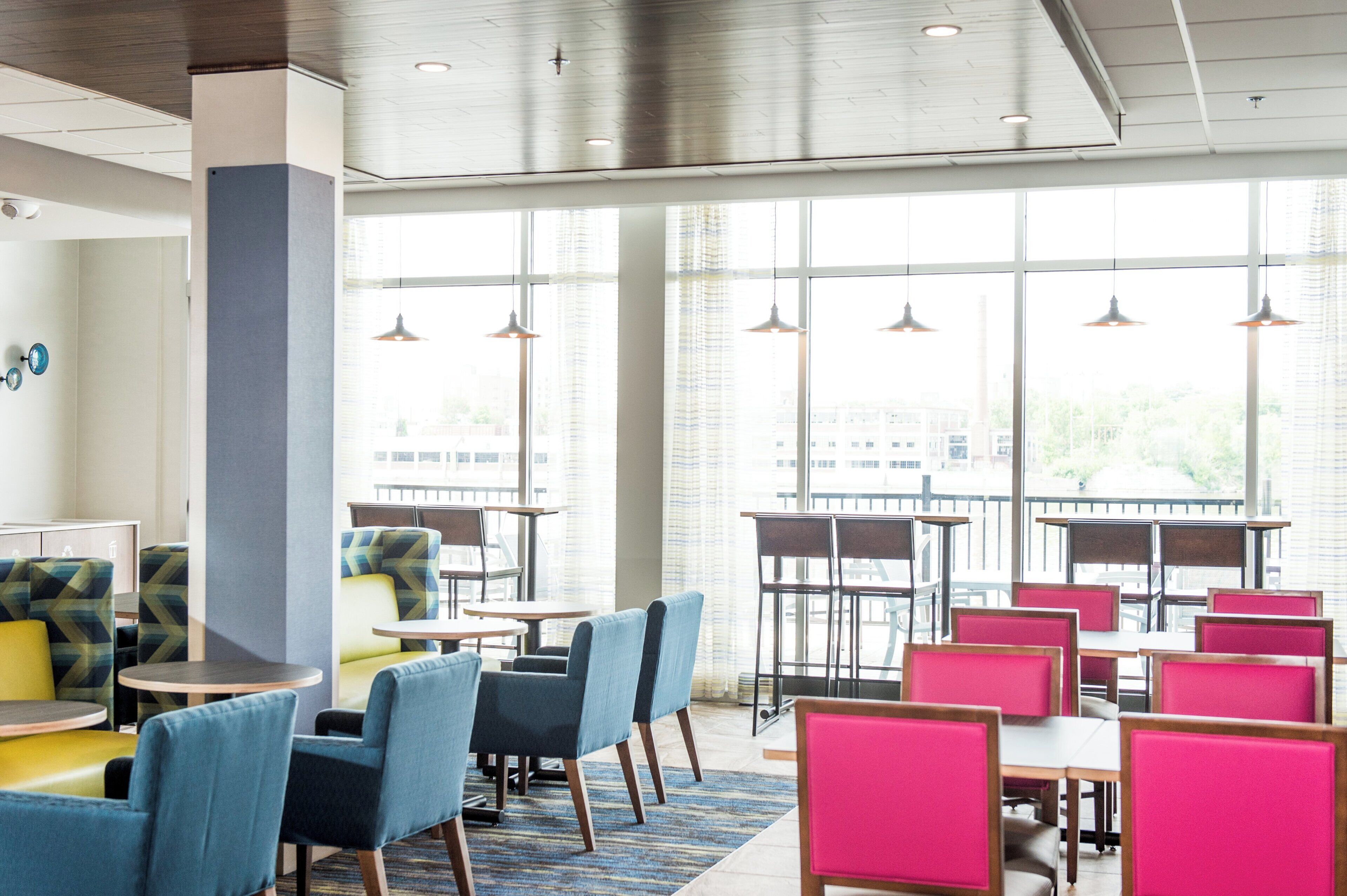 A modern hotel lobby with seating areas, large windows, and pendant lighting.