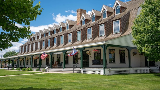 A row of brick buildings with a green porch and American flags. - Sheridan Inn, B/W Signature Collection (Sheridan)