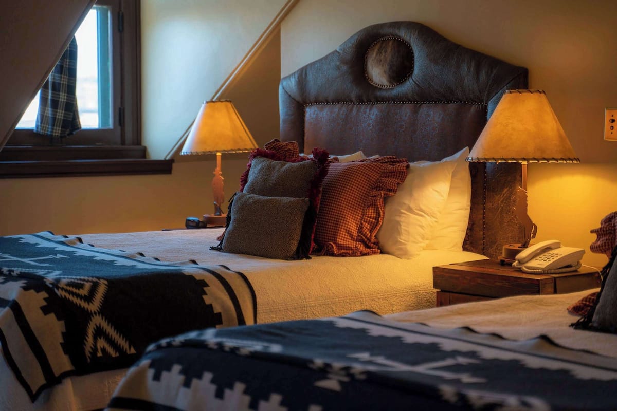 A hotel room with a large bed, two bedside lamps, a telephone, and a window with a view.