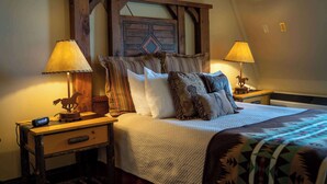 A bedroom with a wooden headboard, multiple pillows, two bedside tables with lamps, and a bed with a patterned blanket. - Sheridan Inn, B/W Signature Collection (Sheridan)