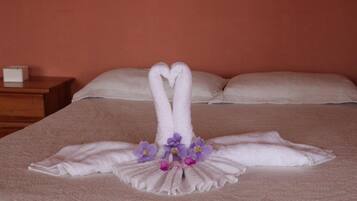 A bed with a towel arrangement in the shape of swans and purple flowers.