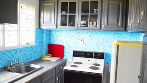 A kitchen with grey cabinets, a white stove, and a blue-tiled backsplash. - On Top of The Bay (Montego Bay)