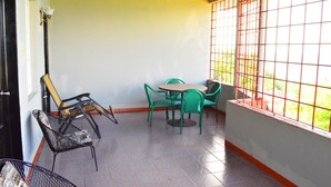 A small, enclosed patio area with a round table and four chairs, a metal chair, and a wooden chair. - On Top of The Bay (Montego Bay)