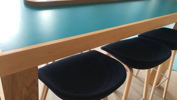 A wooden table with a blue top and metal legs, accompanied by dark blue upholstered chairs.