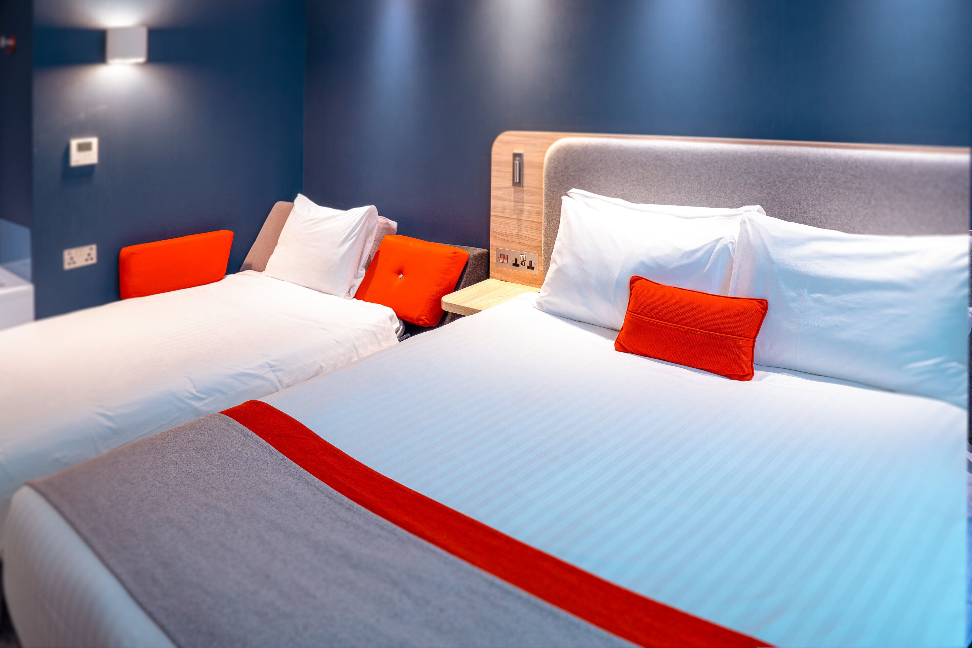 A hotel room with two beds, each with white bedding and red accents.