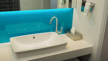 A bathroom with a white sink, a blue accent wall, and a hand dryer.
