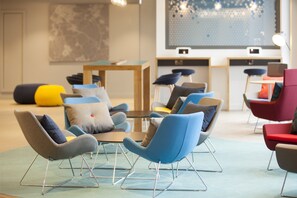 A modern lounge area with multiple seating options including sofas and chairs, a coffee table, and a small table with chairs. - Holiday Inn Express St. Albans - M25, Jct.22 by IHG (St Albans)