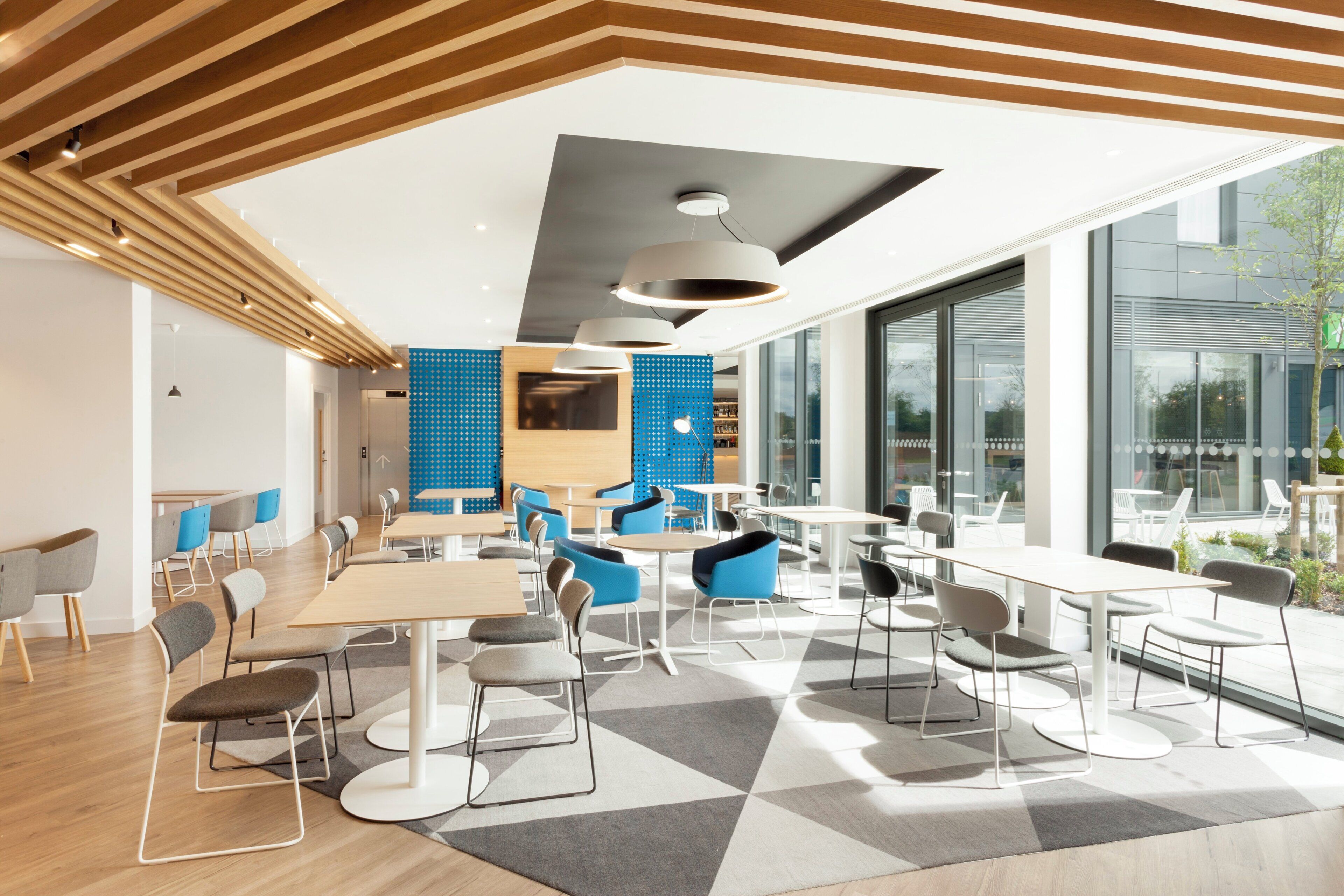 A modern interior with a geometric patterned floor, contemporary furniture, and large windows offering views.