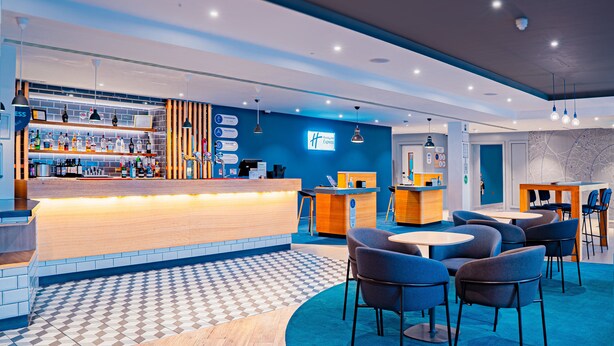 A modern hotel lobby with a bar area, seating, and a check-in counter. - Holiday Inn Express St. Albans - M25, Jct.22 by IHG (St Albans)