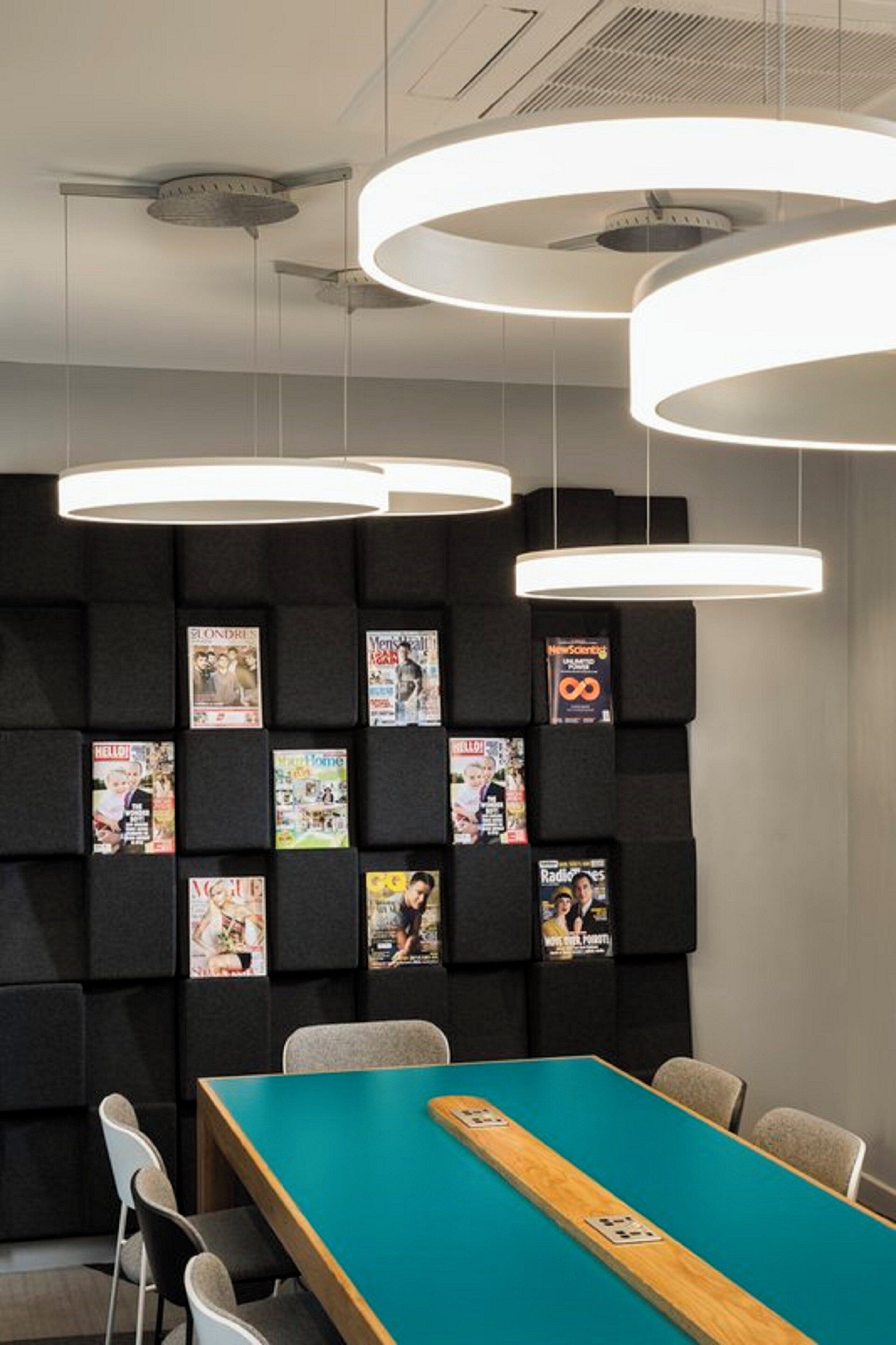 A conference room with a long table, chairs, and a wall with magazine covers.