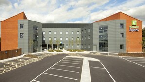 A Holiday Inn Express building with a modern design, featuring a mix of brick and grey panels, and a parking lot in front. - Holiday Inn Express St. Albans - M25, Jct.22 by IHG (St Albans)