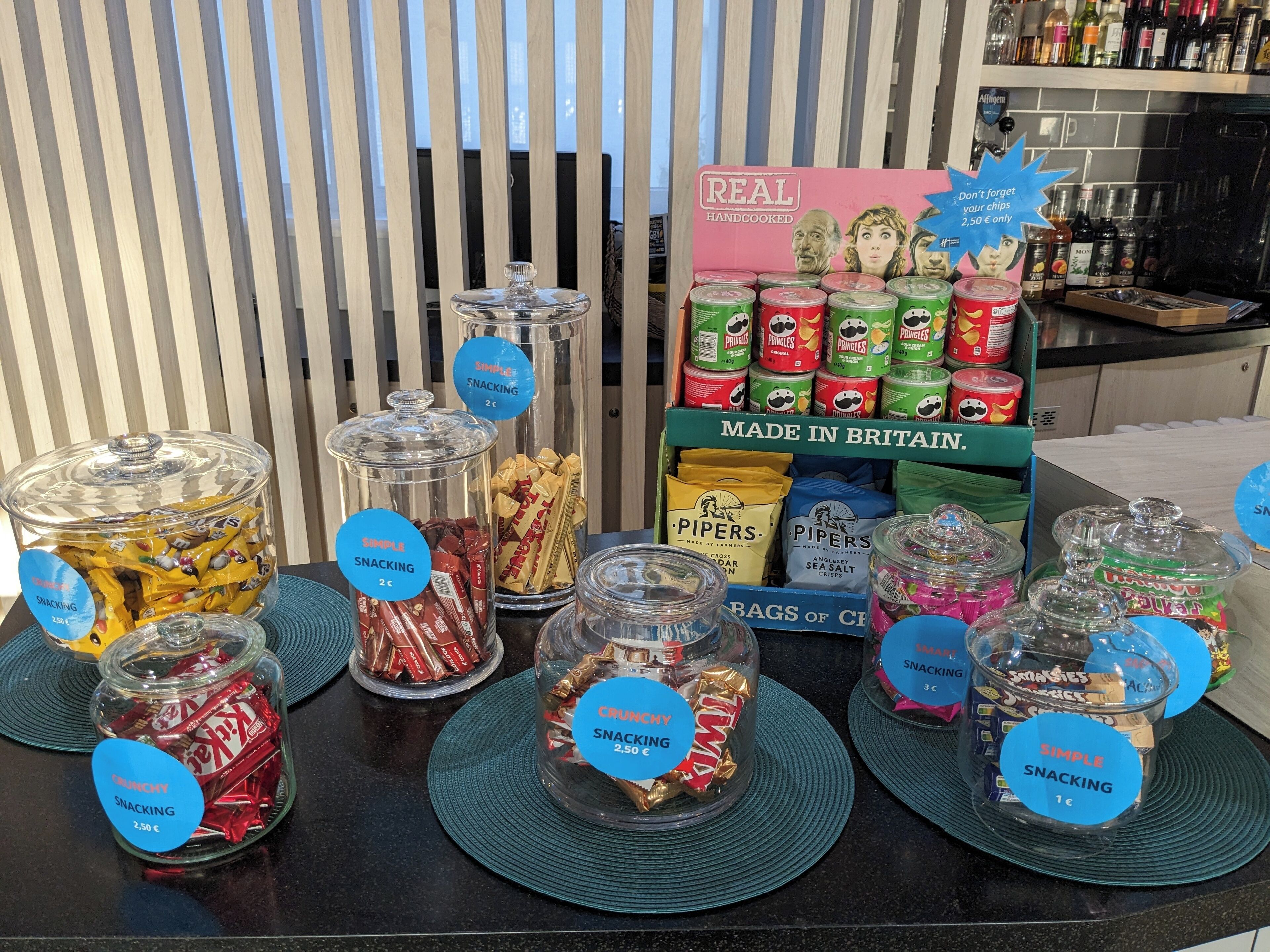 A snack display with various types of snacks and drinks, including Pringles and other brands, priced at 2.50€.