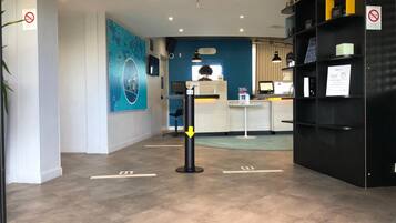 Un área de recepción con mostrador, asientos y una pared azul con diseño circular.