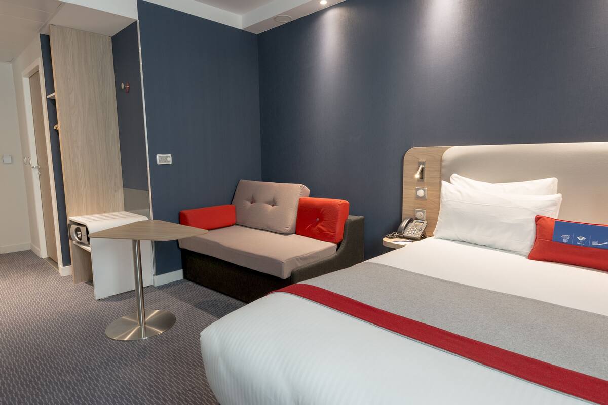 A hotel room with a bed, a desk, and a seating area.