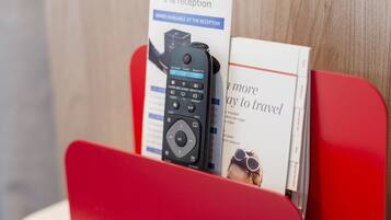 A red and white reception desk with a brochure and a remote control.