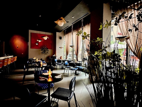 A restaurant with tables and chairs, a bar area, and large windows allowing natural light. - Four Points By Sheraton New York Downtown (New York)