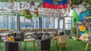 Eine Dachterrasse mit Sitzgelegenheiten im Freien, Pflanzen und einer Flagge.