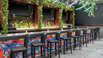 A bar area with a counter, bar stools, and a TV screen.