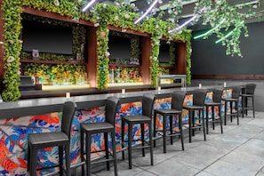 Una zona de bar con mostrador, taburetes y una pantalla de televisión.