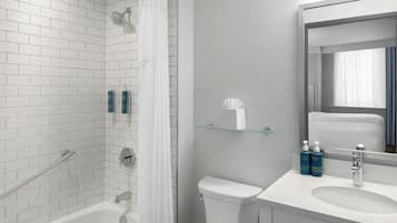 Een moderne badkamer met witte metrotegels, een glazen douchecabine, een wit toilet en een wastafel met een spiegel erboven.