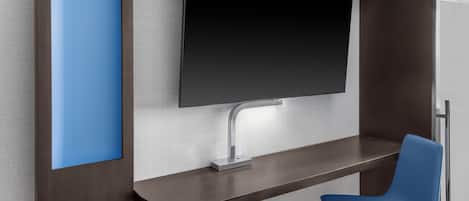 A modern room with a flat-screen TV mounted on the wall, a desk with a chair, and a built-in cabinet.