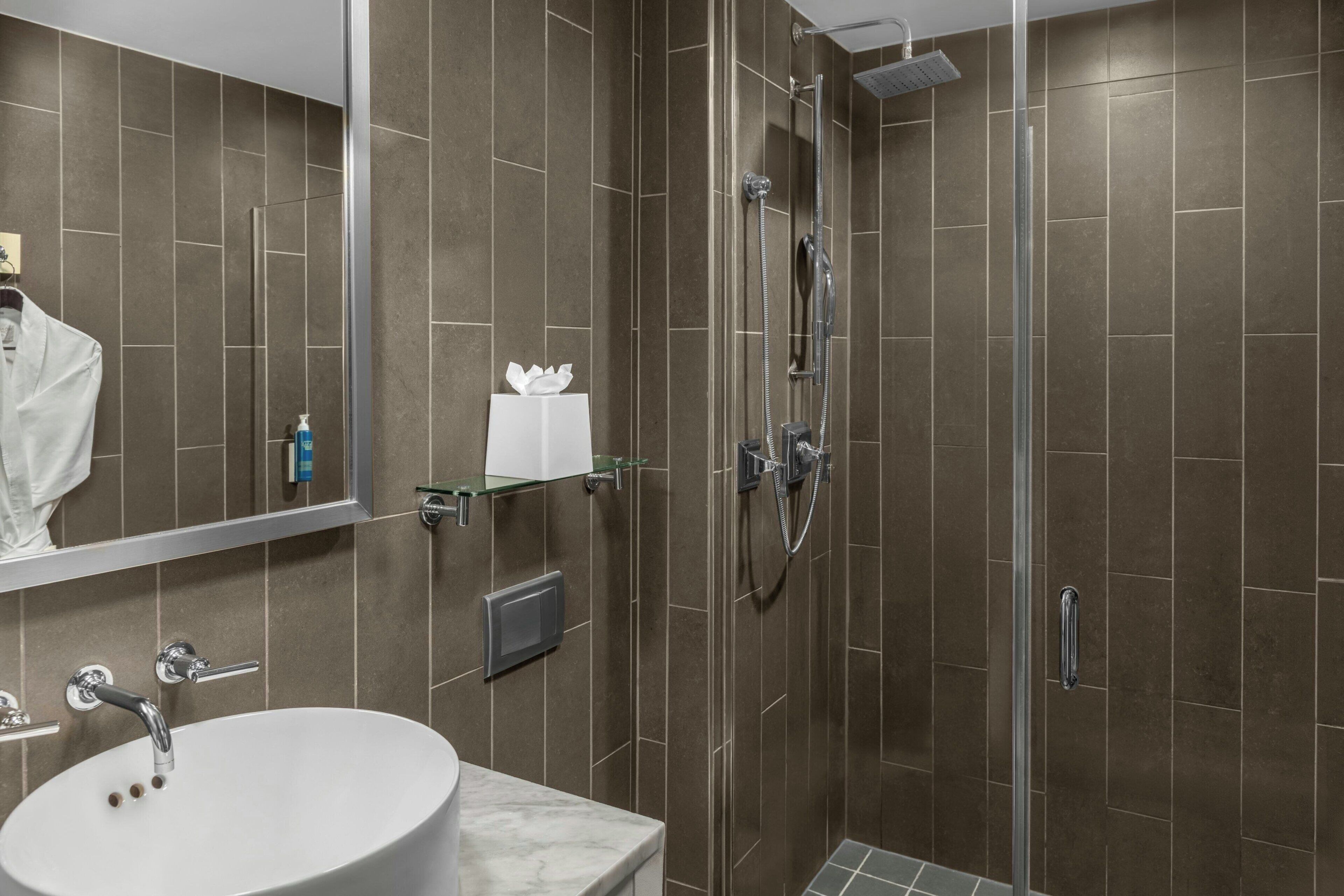 Un bagno moderno con uno specchio grande, un lavabo e una zona doccia.
