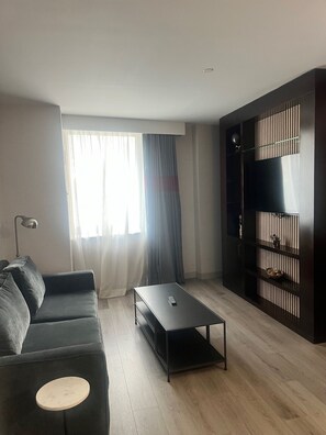 Una sala moderna con un sofá oscuro, una mesa de centro y un mueble de televisión con estantes.