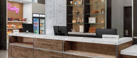 Zona de recepción de un hotel con un letrero de neón, un mini bar, un refrigerador y una barra con una placa de identificación.