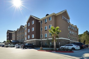 A Staybridge Suites hotel with a parking lot and several vehicles. - Staybridge Suites Tomball - Spring Area by IHG (Tomball)