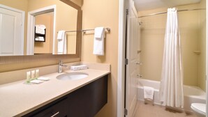 A bathroom with a sink, mirror, and shower area. - Staybridge Suites Tomball - Spring Area by IHG (Tomball)
