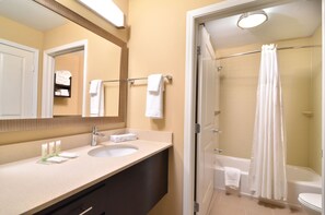 A bathroom with a sink, mirror, and shower area. - Staybridge Suites Tomball - Spring Area by IHG (Tomball)