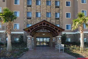 A hotel entrance with a stone facade, multiple windows, and a central archway.