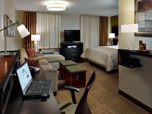 A hotel room with a bed, a desk with a laptop, a TV, a dresser, and a chair. - Staybridge Suites Tomball - Spring Area by IHG (Tomball)