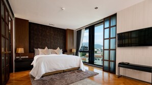 A modern hotel room with a large bed, a TV, and a view of the city. - Sanae' Hotel Nimman (Chiang Mai)