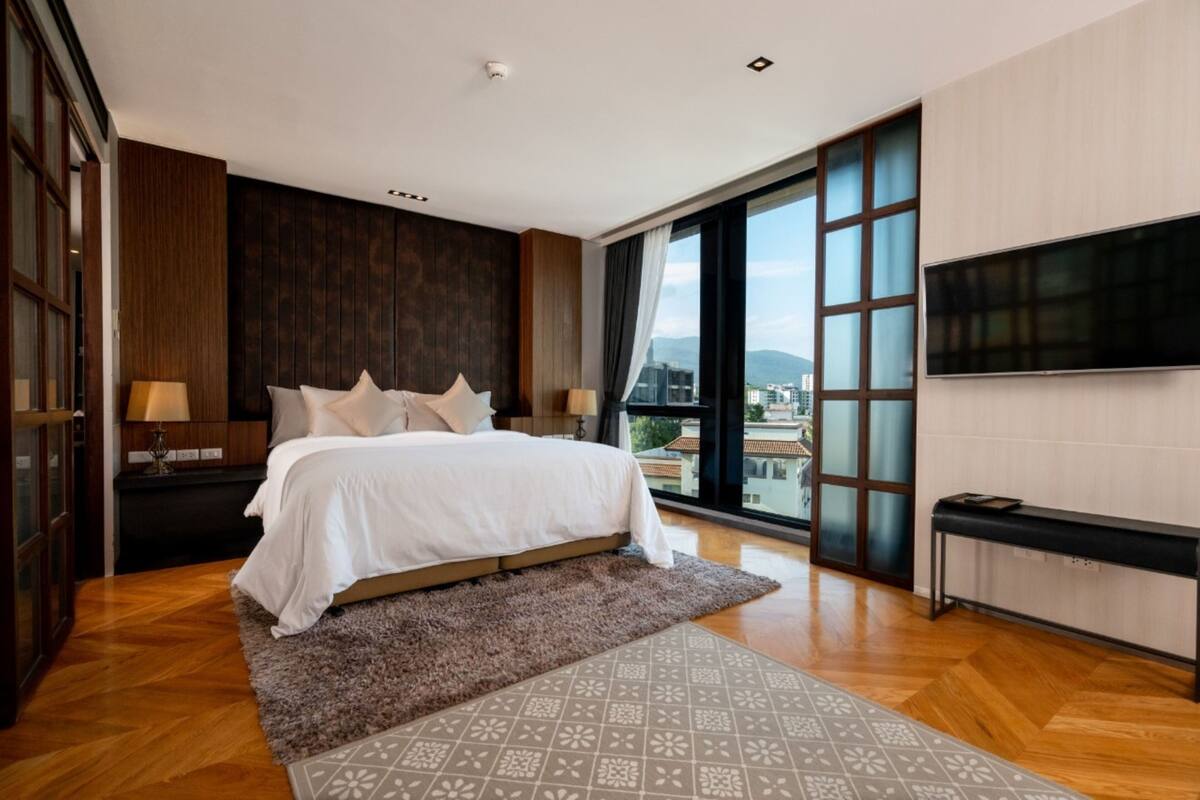Une chambre d’hôtel moderne avec un grand lit, une télévision et une vue sur la ville.