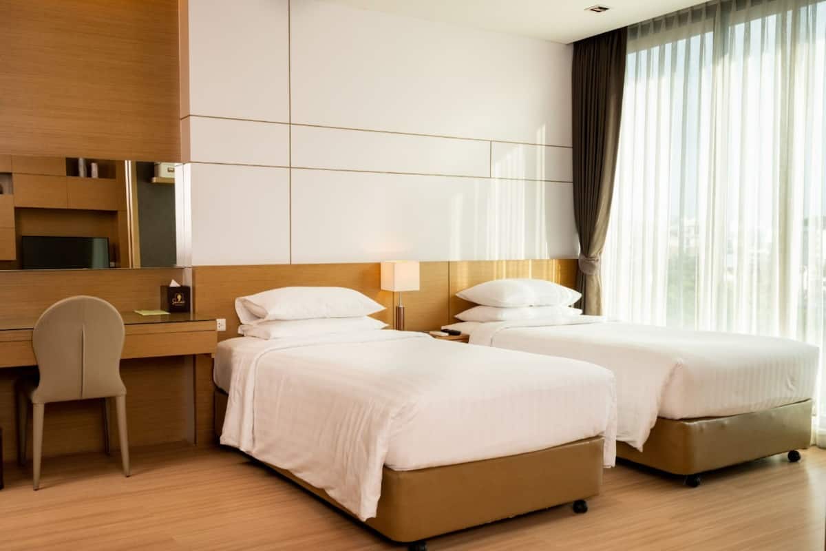 Une chambre d’hôtel avec deux lits, un bureau et une chaise.