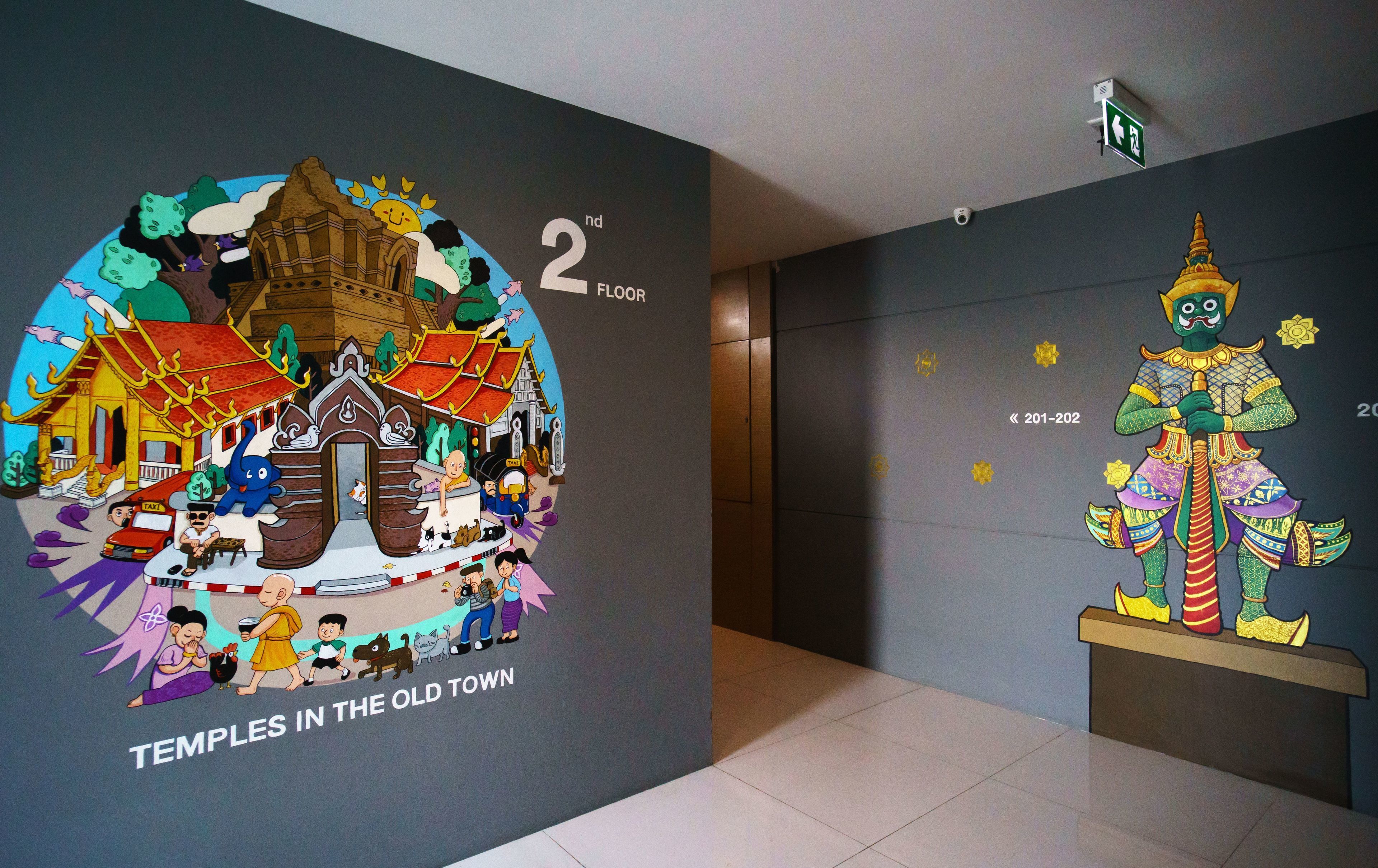 A hotel corridor with a colorful mural depicting a temple scene and a traditional figure.