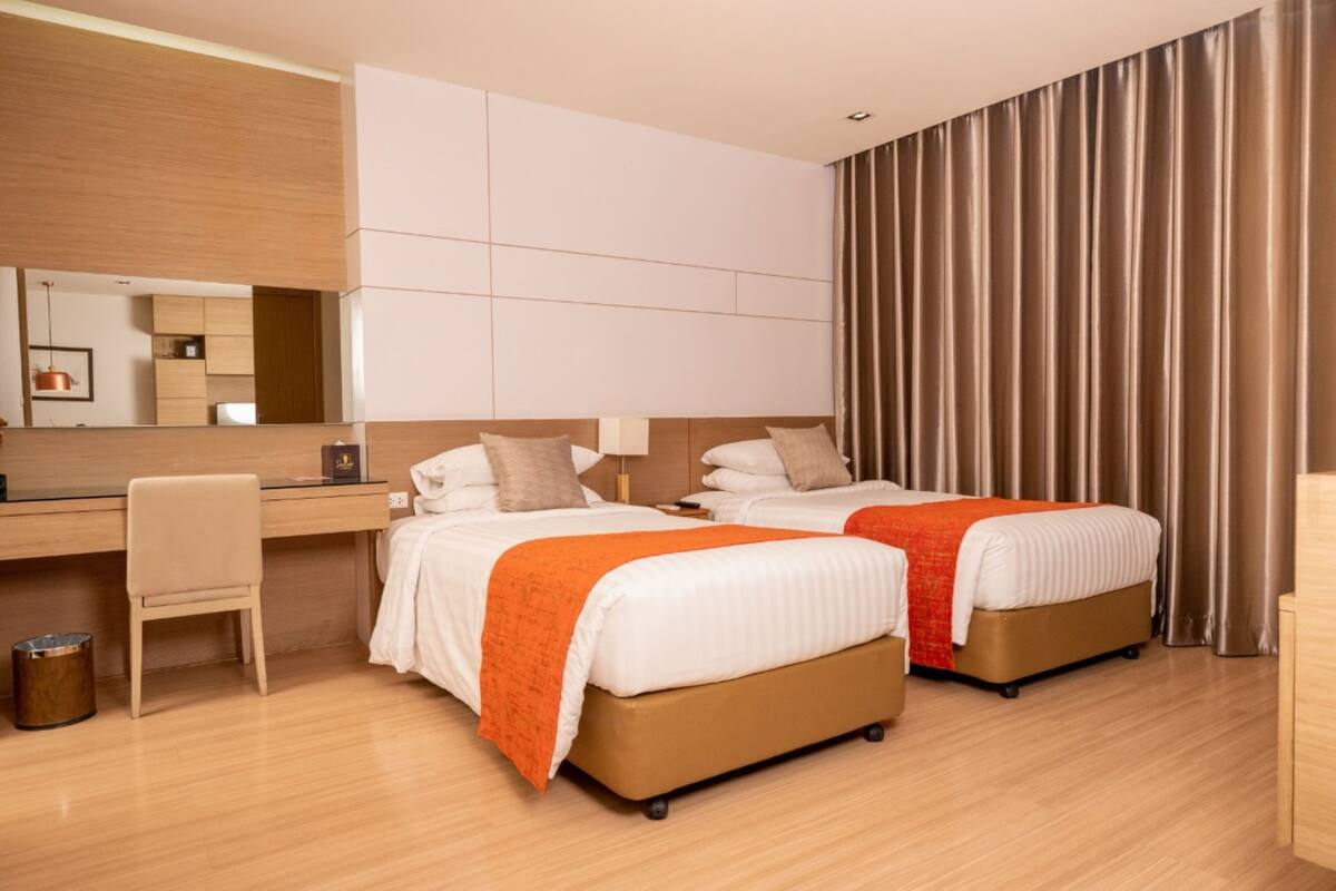 Une chambre d’hôtel avec deux lits, un bureau et une chaise.
