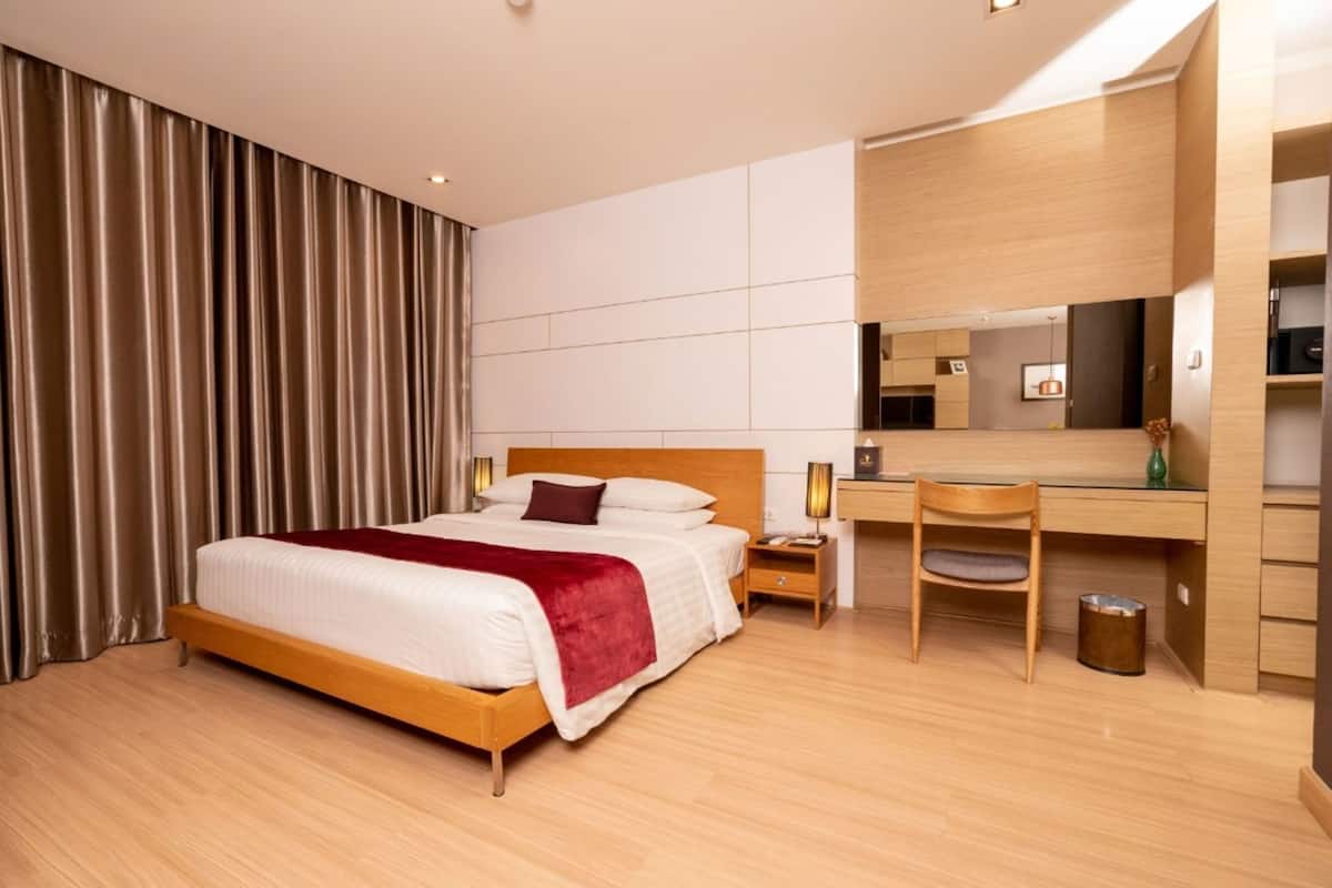 Une chambre d’hôtel équipée d’un lit, d’un bureau, d’une chaise, d’un miroir et d’une poubelle.