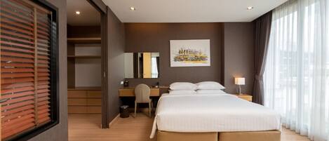 A hotel room with a bed, a desk, a chair, a mirror, and a window with curtains.