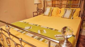 A bed with a metal frame and a yellow bedspread.