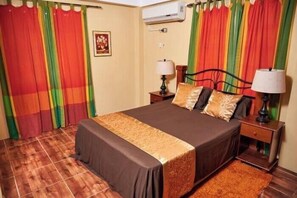 Un dormitorio con una cama, dos mesitas de noche y cortinas.