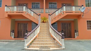 A two-story building with a central staircase, balconies, and a satellite dish. -  JB'S SERENITY STAY (Carnbee)