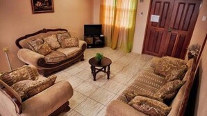 A living room with two sofas, a coffee table, a television, and a door. -  JB'S SERENITY STAY (Carnbee)