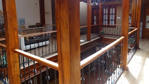 Un intérieur spacieux avec des poutres en bois et une balustrade en verre sur un balcon.