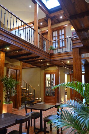A spacious interior with a wooden staircase, a dining area, and a view of the outdoors. - Siena Hotel (Cuenca)
